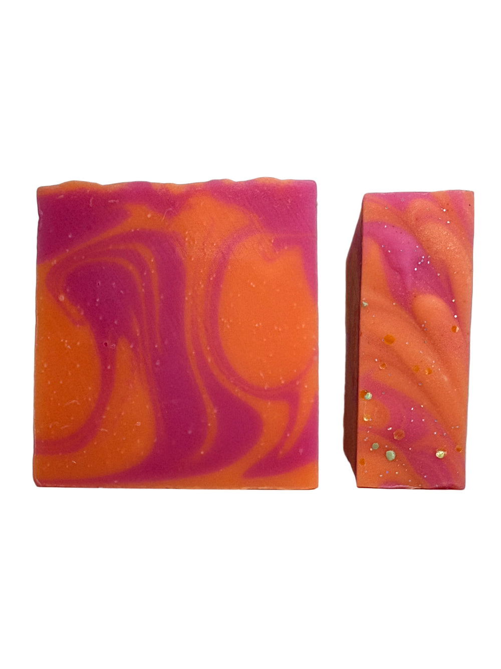 Two marbled soap bars, one orange and pink, the other pink and gold, on a gray background.