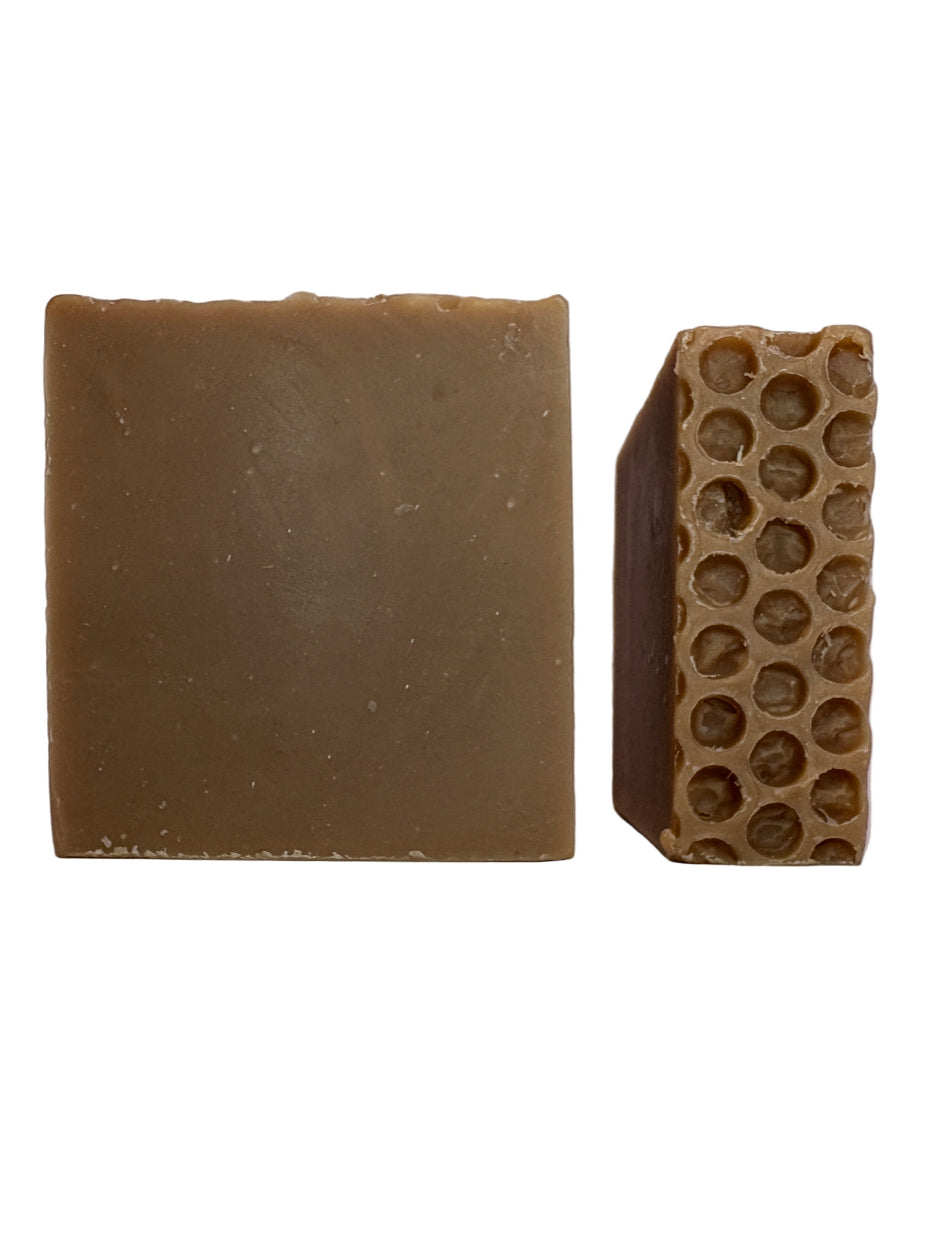 Two oatmeal and honey soap bars, one solid and one with a honeycomb texture, on a white background.