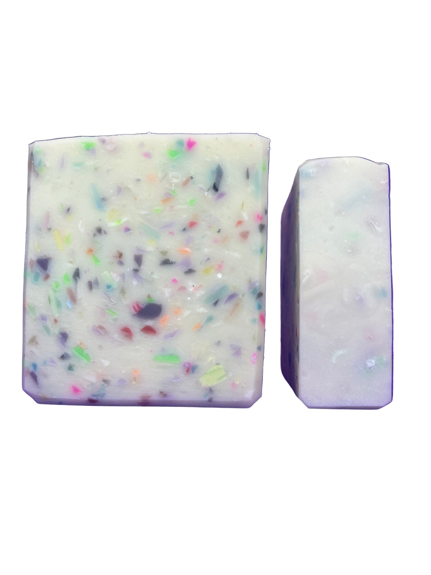 Two bars of soap, one with colorful specks and the other plain, on a white background